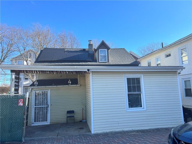 rear view of property with a patio area and solar panels