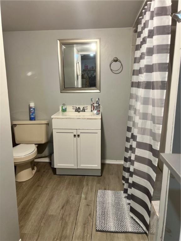 bathroom featuring curtained shower, toilet, vanity, and hardwood / wood-style flooring