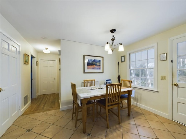 tiled dining area featuring a chandelier