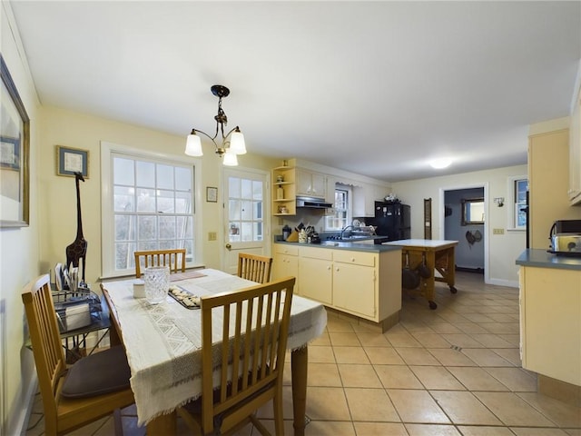 kitchen featuring black fridge, sink, decorative light fixtures, an inviting chandelier, and light tile patterned flooring