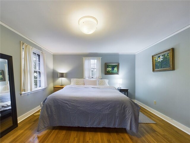 bedroom featuring crown molding and dark hardwood / wood-style flooring