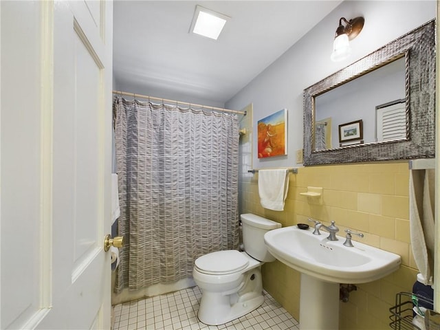 bathroom with tile patterned floors, sink, a shower with shower curtain, toilet, and tile walls