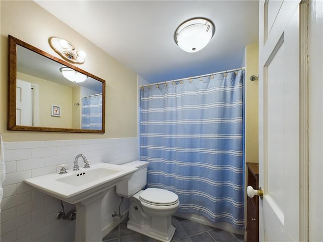 bathroom with toilet, tile walls, curtained shower, and tile patterned flooring