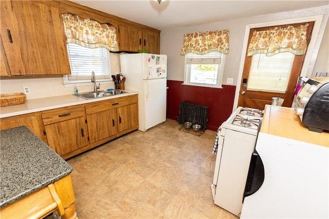 kitchen featuring plenty of natural light, white appliances, radiator heating unit, and sink