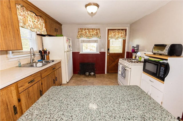 kitchen featuring white appliances, radiator, a healthy amount of sunlight, and sink