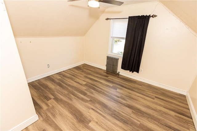 additional living space featuring hardwood / wood-style floors, ceiling fan, radiator heating unit, and vaulted ceiling