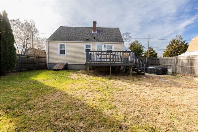 back of property featuring a deck, a yard, and a hot tub