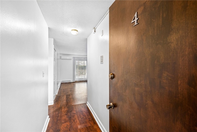 corridor with a wall mounted air conditioner, a baseboard heating unit, a textured ceiling, and dark wood-type flooring