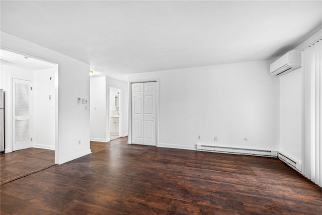 spare room featuring a wall unit AC, dark hardwood / wood-style flooring, a textured ceiling, and baseboard heating