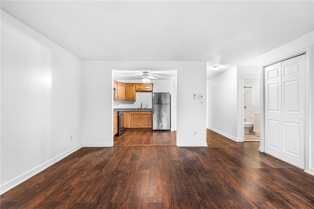 unfurnished living room with dark hardwood / wood-style floors, ceiling fan, and sink