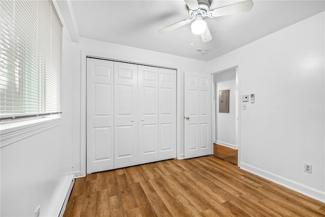 unfurnished bedroom featuring ceiling fan, electric panel, light hardwood / wood-style floors, a textured ceiling, and a closet