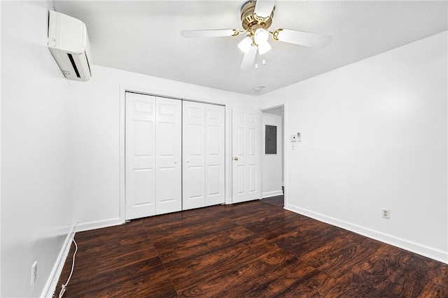 unfurnished bedroom with a wall mounted AC, ceiling fan, dark wood-type flooring, and a textured ceiling