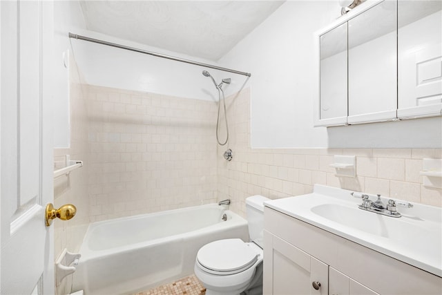 full bathroom with tiled shower / bath, vanity, tile walls, and toilet