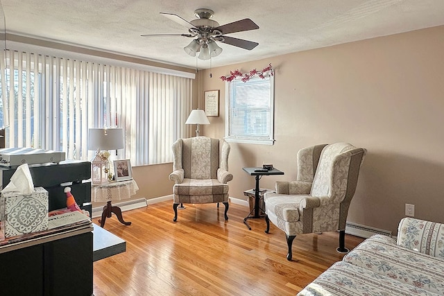 sitting room with a textured ceiling, hardwood / wood-style flooring, ceiling fan, and a baseboard heating unit