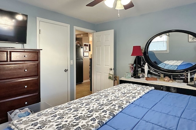 bedroom with ceiling fan, black refrigerator, and light tile patterned flooring