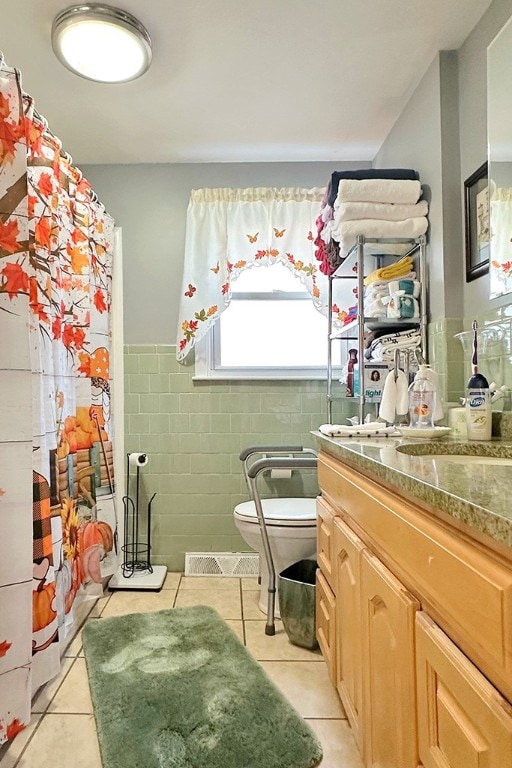 bathroom with tile patterned floors, vanity, toilet, and tile walls