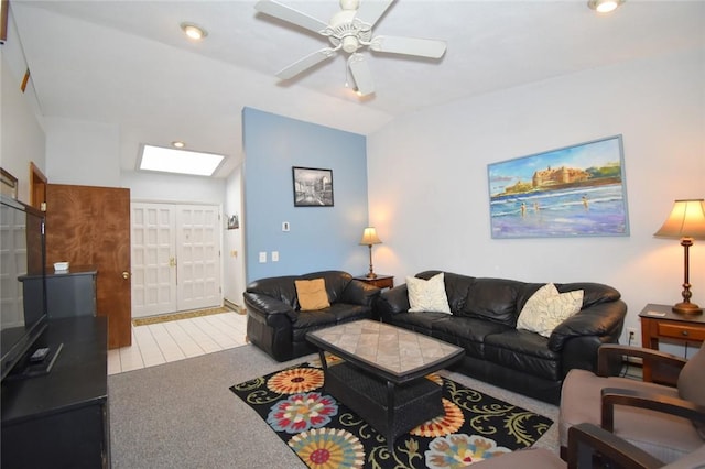 carpeted living room featuring ceiling fan and vaulted ceiling with skylight