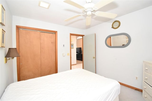 bedroom with a closet, ceiling fan, and light colored carpet