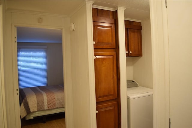 laundry room featuring wooden walls, cabinets, crown molding, and washer / clothes dryer