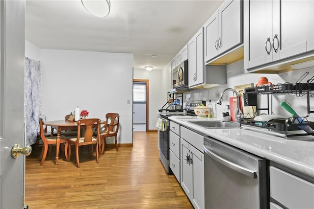 kitchen featuring sink, stainless steel appliances, tasteful backsplash, and light hardwood / wood-style flooring