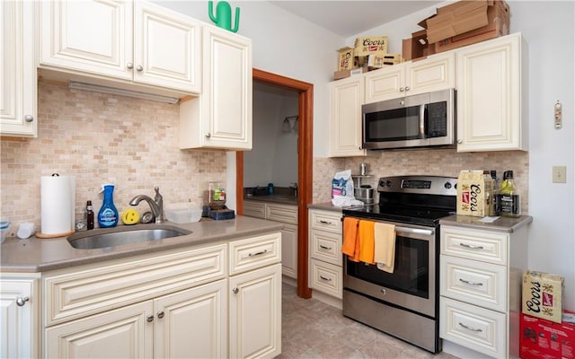 kitchen with decorative backsplash, sink, light tile patterned flooring, and stainless steel appliances