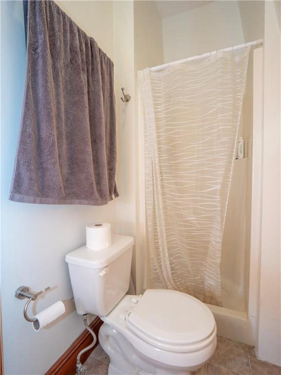 bathroom featuring tile patterned flooring, a shower with curtain, and toilet