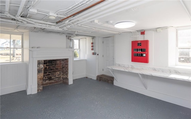 basement with plenty of natural light, a fireplace, and electric panel