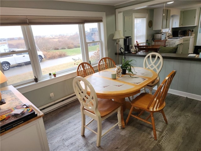 dining space with sink, wood-type flooring, and baseboard heating