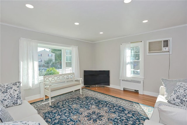 living room featuring radiator, a wealth of natural light, ornamental molding, and hardwood / wood-style flooring