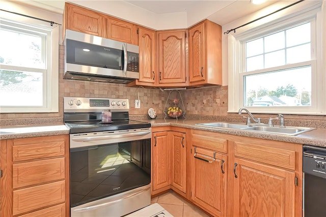 kitchen with a healthy amount of sunlight, sink, light tile patterned floors, and stainless steel appliances