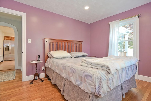 bedroom with stainless steel fridge and light wood-type flooring