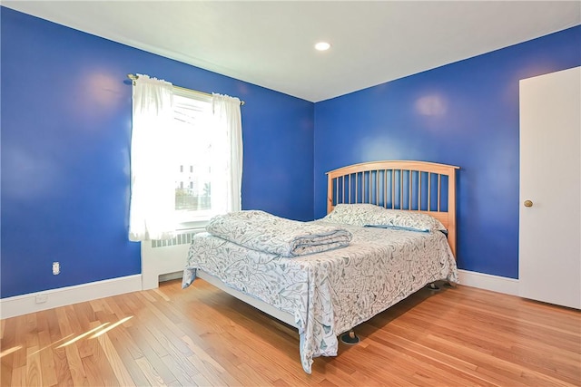 bedroom featuring radiator and hardwood / wood-style floors