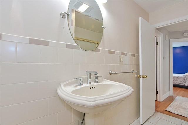 bathroom with wood-type flooring, tile walls, and sink