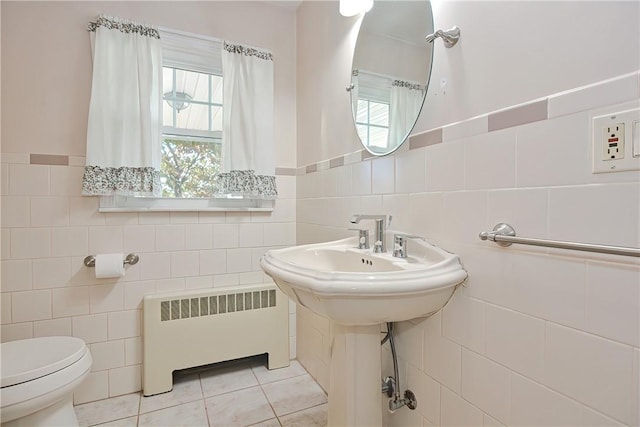 bathroom with tile patterned floors, radiator, tile walls, and toilet