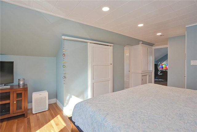 bedroom featuring a closet, lofted ceiling, and light wood-type flooring