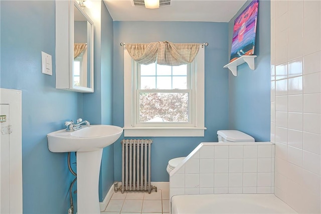 bathroom with tile patterned floors, toilet, sink, and radiator