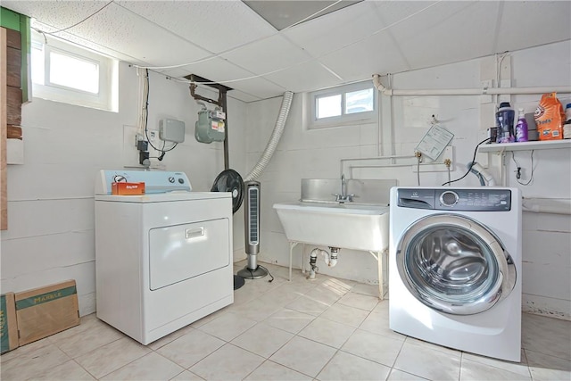 laundry area featuring washing machine and clothes dryer, sink, and light tile patterned floors