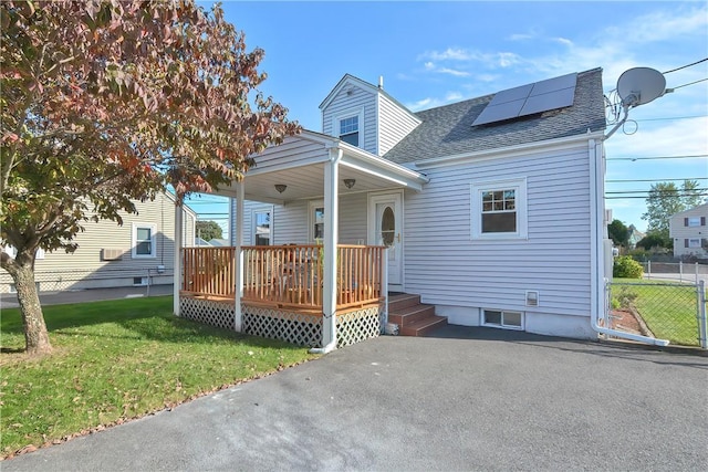 view of front of home with solar panels, a porch, and a front lawn