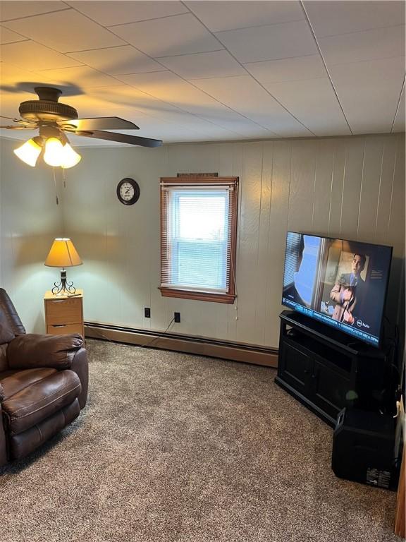 living area with carpet, ceiling fan, baseboard heating, and wood walls