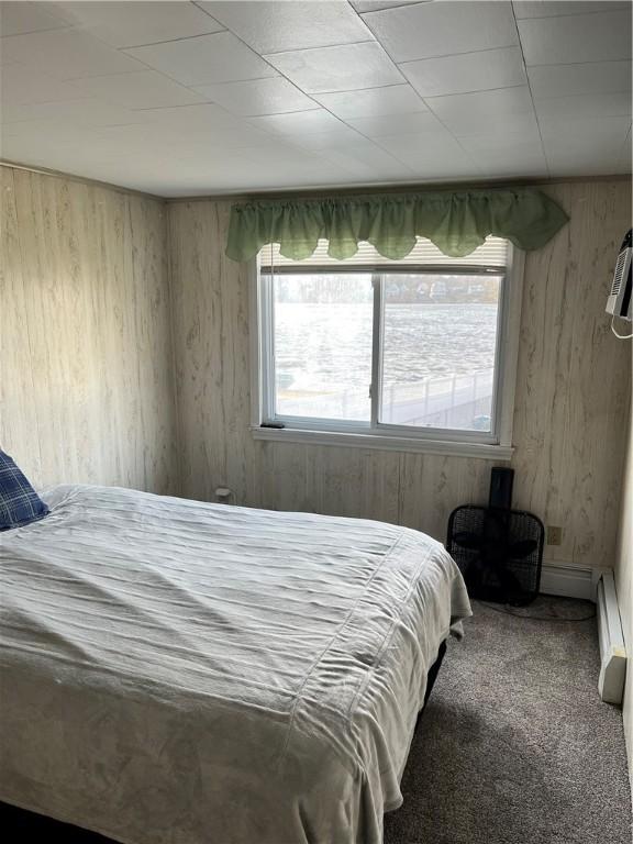 carpeted bedroom featuring wooden walls