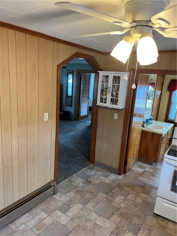 kitchen with light carpet, baseboard heating, white range with electric stovetop, crown molding, and wooden walls