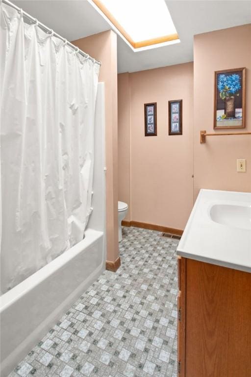 full bathroom featuring a skylight, vanity, shower / tub combo, and toilet