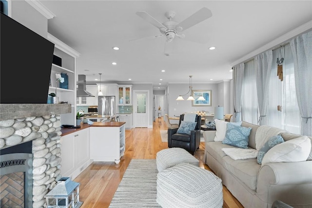 living room featuring a fireplace, ceiling fan, light hardwood / wood-style flooring, and ornamental molding