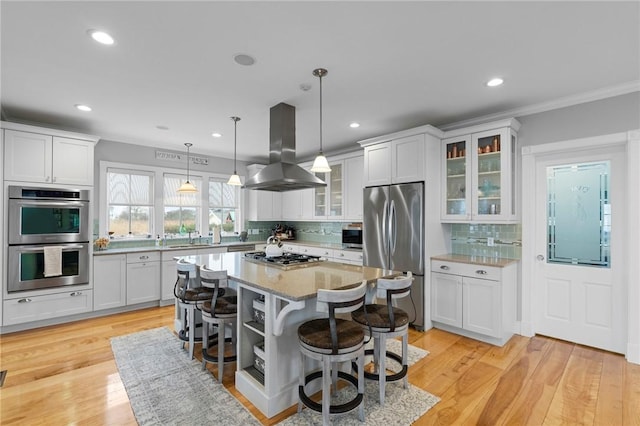 kitchen with island exhaust hood, decorative backsplash, a breakfast bar, a kitchen island, and appliances with stainless steel finishes