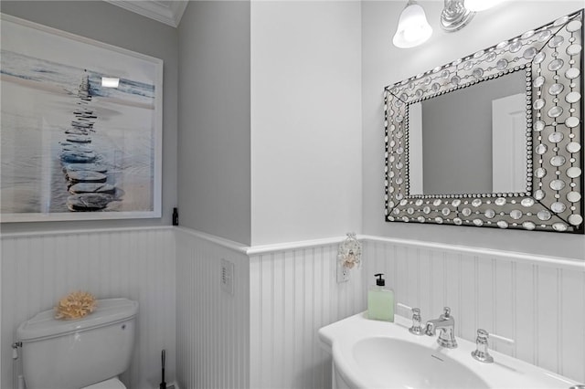 bathroom with toilet, ornamental molding, and sink