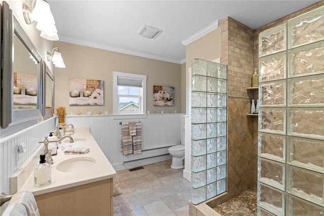 bathroom with a tile shower, crown molding, vanity, and toilet