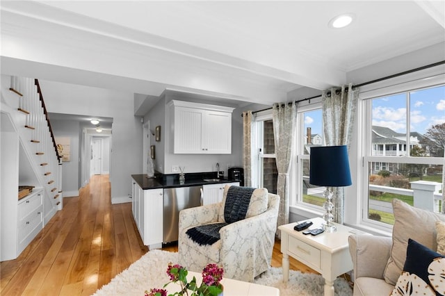 kitchen featuring white cabinets, light wood-type flooring, stainless steel dishwasher, and a healthy amount of sunlight