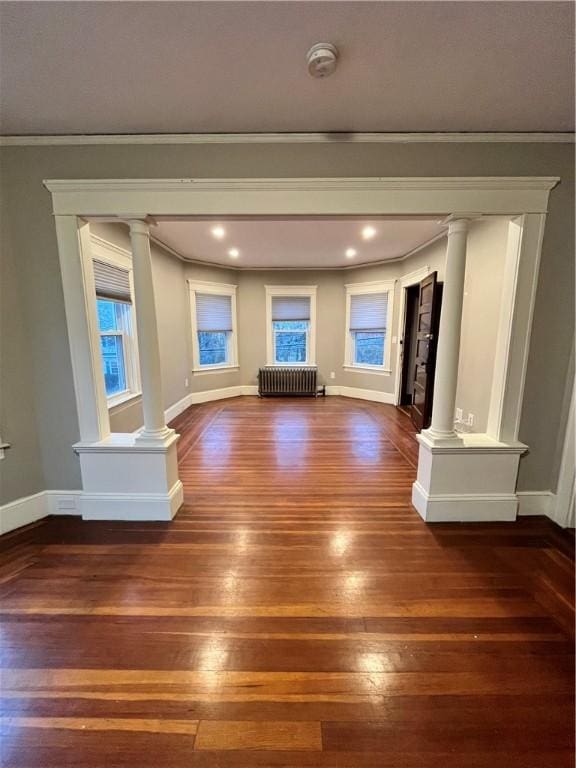 unfurnished living room with radiator heating unit, dark wood-type flooring, and ornamental molding