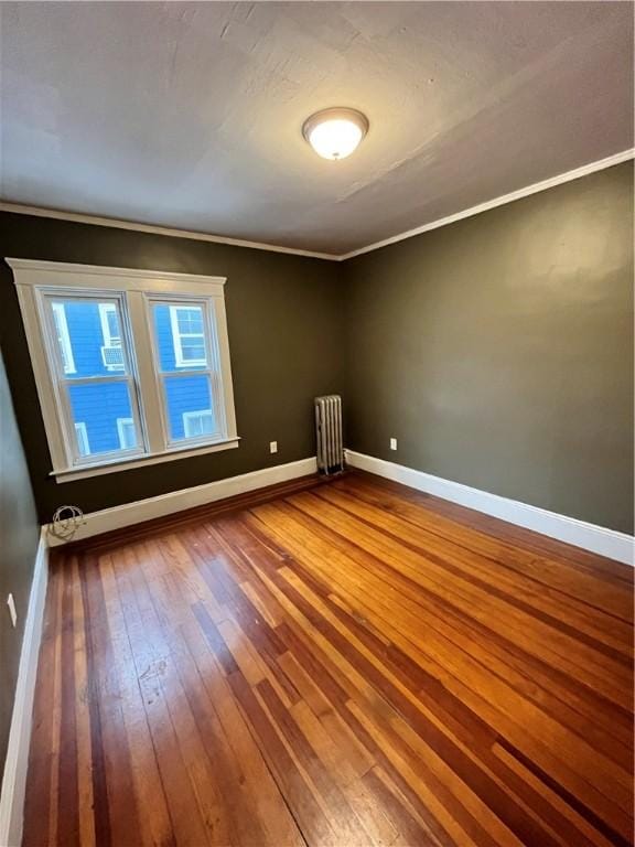 empty room with radiator heating unit, crown molding, and hardwood / wood-style floors