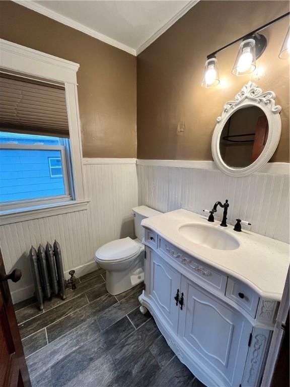 bathroom featuring vanity, toilet, radiator, and crown molding